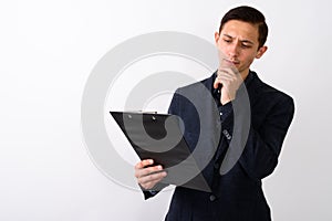 Studio shot of young handsome businessman thinking while looking