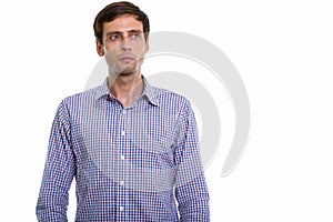 Studio shot of young handsome businessman thinking while looking