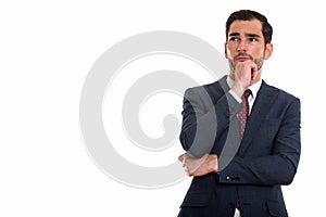 Studio shot of young handsome businessman thinking while looking