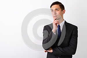 Studio shot of young handsome businessman thinking while looking