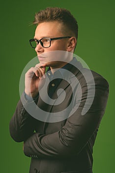 Studio shot of young handsome businessman against green background