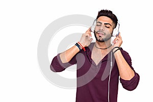 Studio shot of young handsome Indian man listening to music isol