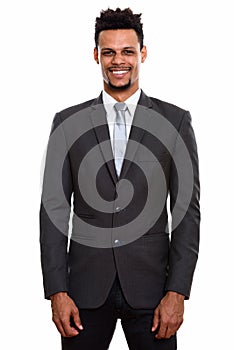 Studio shot of young happy African businessman smiling while st