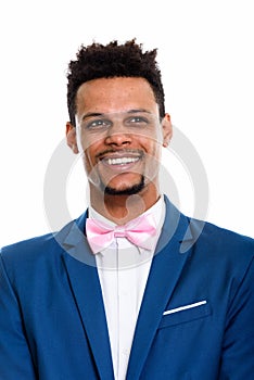 Studio shot of young happy African businessman smiling while thi