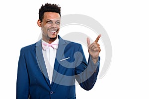 Studio shot of young happy African businessman smiling while thi