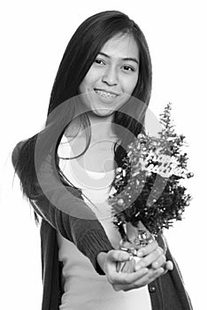 Studio shot of young happy Asian teenage girl smiling and giving Happy New Year tree