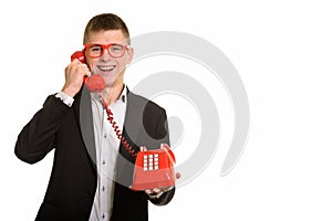 Studio shot of young happy businessman smiling and talking on ol