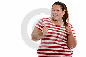 Studio shot of young happy fat Asian woman smiling and giving th