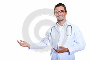 Studio shot of young happy man doctor smiling while showing some