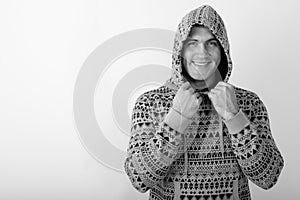 Studio shot of young happy muscular man smiling and holding hoodie against white background