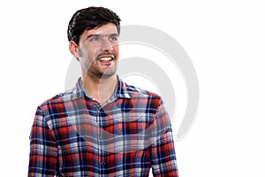 Studio shot of young happy Persian man smiling and thinking whil