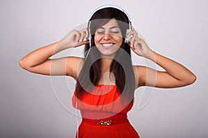 Studio shot of young happy Persian woman smiling while listening