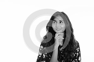 Studio shot of young happy Persian woman smiling and thinking while looking up