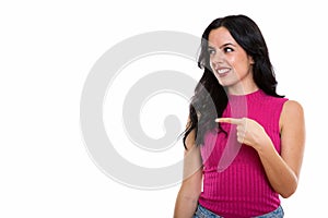 Studio shot of young happy Spanish woman smiling while pointing