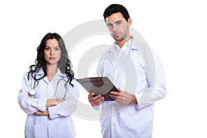 Studio shot of young man doctor holding clipboard and woman doct