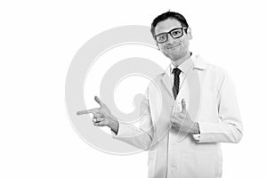 Studio shot of young man doctor pointing to the side and giving thumb up