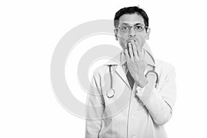 Studio shot of young man doctor wearing eyeglasses while looking shocked