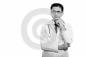 Studio shot of young man doctor wearing eyeglasses while thinking and looking up