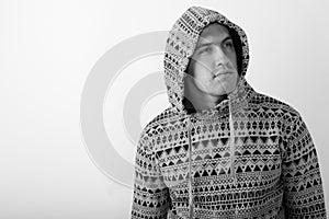 Studio shot of young muscular man wearing hoodie while thinking and looking up against white background