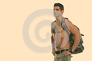 Studio shot of young muscular Persian man posing shirtless with hands on hips