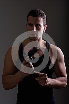 Studio shot of young muscular Persian man reloading gun while th