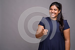 Young overweight beautiful Indian woman against gray background