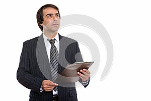 Studio shot of young Persian businessman holding clipboard while