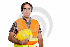 Studio shot of young Persian man construction worker holding saf