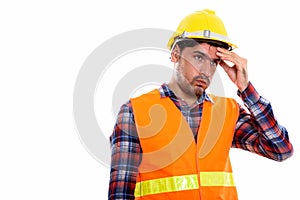 Studio shot of young Persian man construction worker looking str