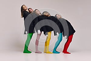 Studio shot of young stylish beautiful fashion models in black jackets and multi colored tights posing over grey