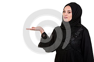 Studio shot of young woman wearing traditional arabic clothing. she`s holding her hand to the side