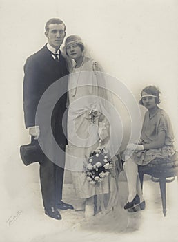Studio wedding photograph of the marriage of a young couple around 1925 with the bridesmaid or a child from a previous marriage