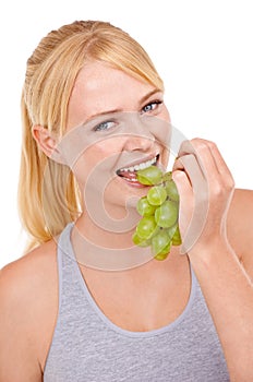 Studio, woman and portrait with eating grapes for vitamin c, vegan and diet for wellness. Food, face and happy person