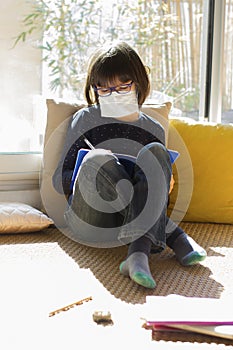 Studious lockdown kid with face mask writing while school shutdown