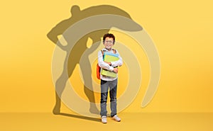 A studious young boy with curly hair and glasses holds his school books tightly