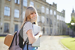 Study abroad. Happy university student with laptop in campus photo