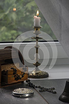 Chandelier with household items on the window, cross, women`s mirror.