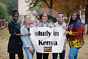 Study in Kenya. Group of five african college students on campus at university yard hold white blank. Abroad countries for student