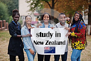 Study in New Zealand. Group of five african college students on campus at university yard hold white blank. Abroad countries for