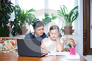 Study online with video call teacher. Young girl and her mother learn online at home.Social distancing