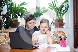 Study online with video call teacher. Young girl and her mother learn online at home.Social distancing