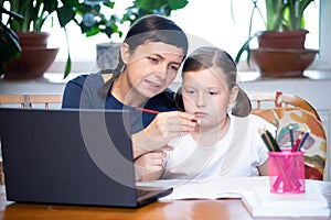 Study online with video call teacher. Young girl and her mother learn online at home.Social distancing