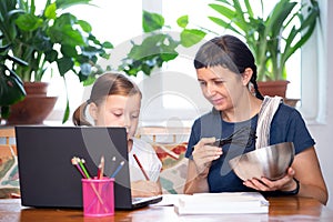 Study online with video call teacher. Young girl and her mother learn online at home.Social distancing