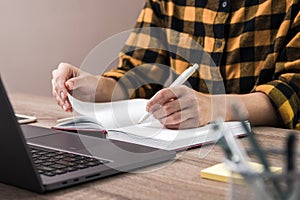 The study is power. close up hands of a businesswoman, student or freelancer in yellow shirt making notes in her