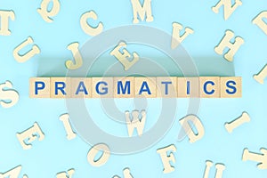 Study pragmatics in linguistics concept. Wooden blocks word typography flat lay in blue background.