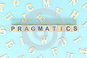 Study pragmatics in linguistics concept. Wooden blocks word typography flat lay in blue background. photo