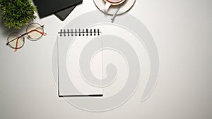 Study table with blank page of spiral notebook on white background