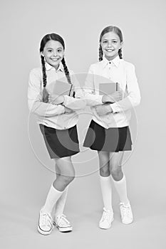 Studying english literature. Little girls holding books of language and literature on yellow background. Small children