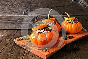 Stuffed autumn mini pumpkins with rice, cranberries, cabbage and nuts, side view on platter against rustic wood