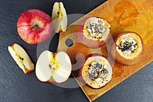 Stuffed baked apples with sezame seeds and walnuts over the black slate stone background